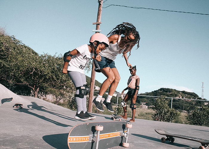 2 girls jumping over a skateboard in Jamaica